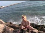 Blonde Aude strips on the rocks