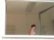 Short haired girl washes windows topless