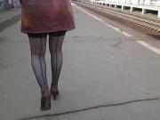 Girl in seamed stockings walking on a train station