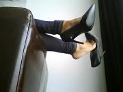 Hot stilettos dangling off of leather couch