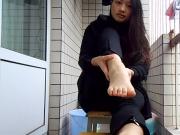 Pretty Asian on patio spreading toes