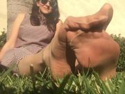 Stretching toes and arches in pantyhose on grass