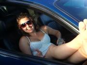 Curly haired brunette dangles cute feet out of car